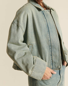 Veste en denim bleu clair, coupe droite et légèrement oversize, tissu 100 % coton avec une texture douce et un style décontracté parfait pour l'été.