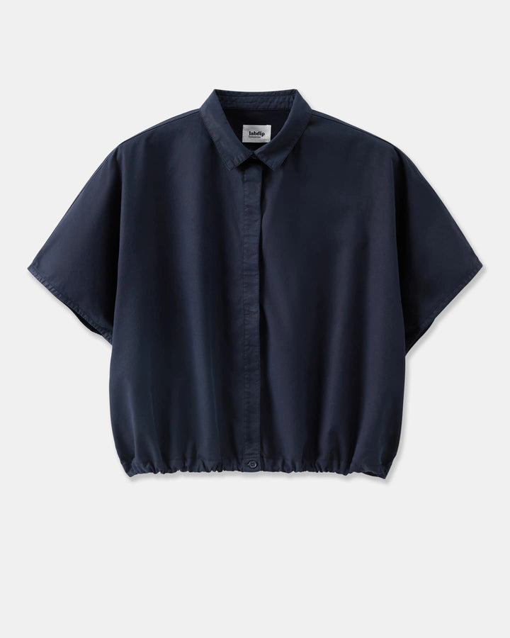 Chemise fluide en popeline bleu marine, coupe ample avec col classique et bas élastiqué, idéale pour un style décontracté et élégant.