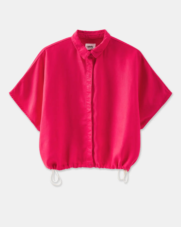 chemise fluide femme en tissu léger fuchsia avec col classique et manches courtes larges, coupe ample ajustable par cordons de serrage à la base