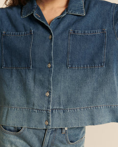 Chemise en denim 100 % coton dégradé bleu indigo, coupe droite et manches longues, avec deux poches plaquées carrées sur la poitrine.
