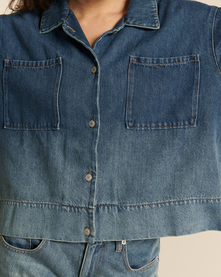 Chemise en denim 100 % coton dégradé bleu indigo, coupe droite et manches longues, avec deux poches plaquées carrées sur la poitrine.