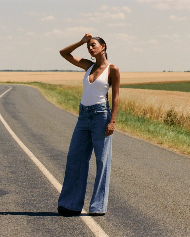Jean en denim bleu clair 100 % coton avec une coupe large et fluide, adaptée à toutes les morphologies, portée en été avec style décontracté.