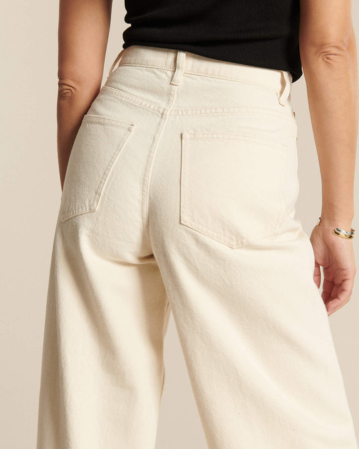 Jean femme en denim écru 100 % coton avec coupe large et taille haute, offrant un ajustement confortable et adapté à toutes les morphologies.
Porté par le mannequin de dos