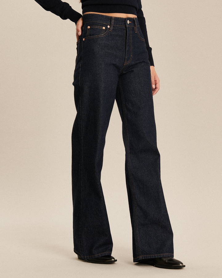 Jean en denim foncé 100 % coton avec coupe flare et taille haute, offrant un tombé souple et élégant adapté à toutes morphologies.