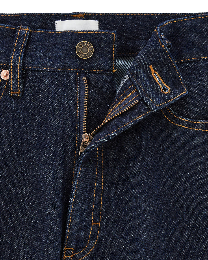 Jean droit en denim brut foncé avec coutures contrastées, bouton métallique gravé, fermeture éclair et matière 100 % coton adaptée aux morphologies féminines.