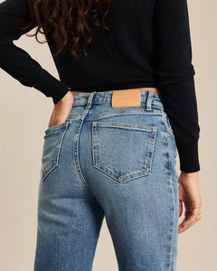 Jean coupe bootcut en denim bleu rétro, matière coton avec légère décoloration, taille moyenne s'ajustant parfaitement aux morphologies féminines.