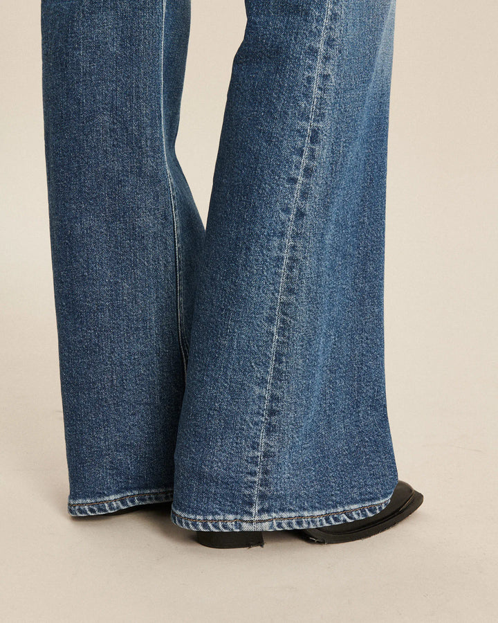 Jean femme en denim 100 % coton bleu moyen avec coupe bootcut évasée à partir du genou, offrant un tombé fluide et un ajustement confortable.