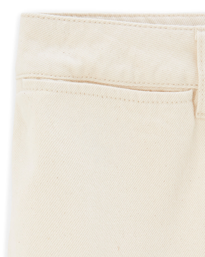 Détail de jean féminin en denim écru clair, matière 100% coton avec une coupe droite et un tissage visible pour un style estival naturel et élégant.
