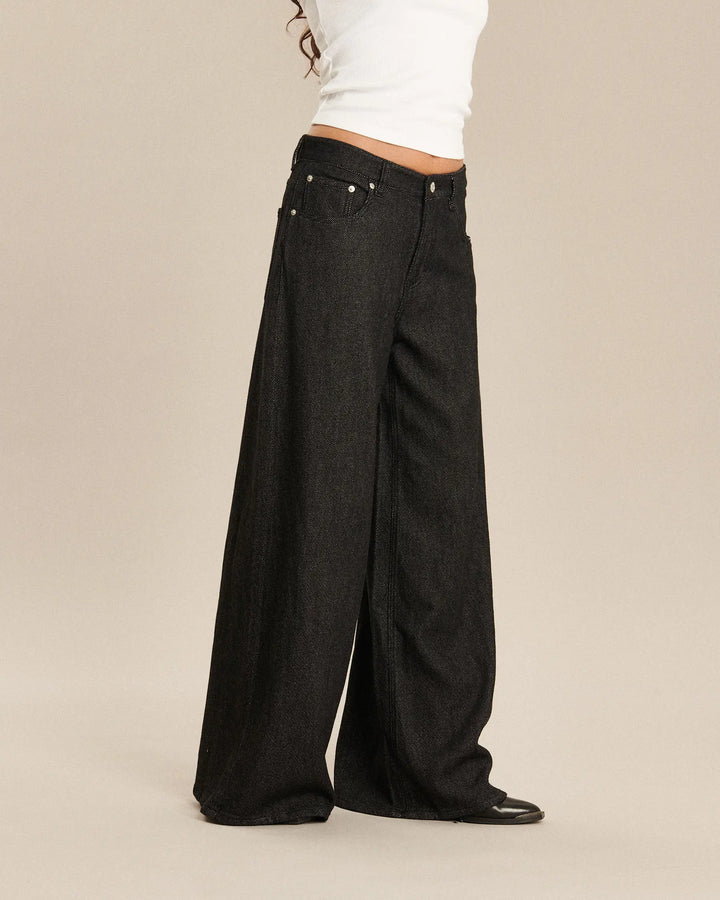 Jean large en denim foncé de coupe ample et fluide, conçu pour s’adapter à toutes les morphologies féminines avec un coton de qualité et un style contemporain.