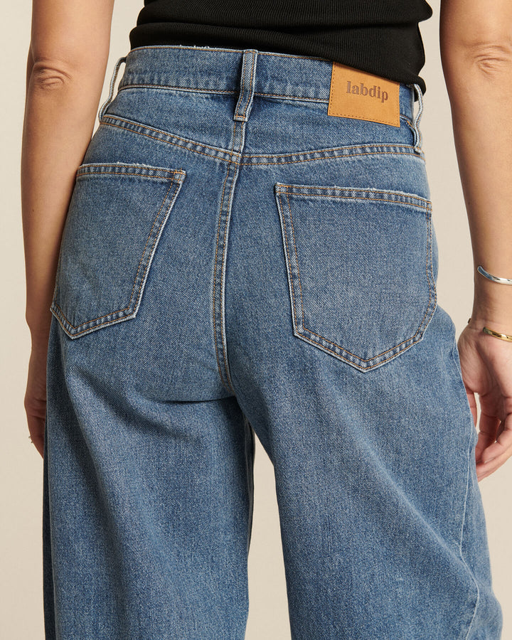 Jean femme en denim bleu clair, coupe droite et taille haute avec poches arrière classiques, en coton 100%, adapté à toutes les morphologies.