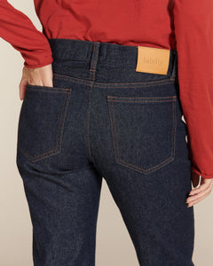 Jean droit bleu foncé en denim 100% coton avec coutures visibles contrastées, conçu pour épouser toutes les morphologies féminines avec un style classique et intemporel.