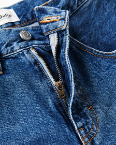 Jean en denim bleu moyen 100 % coton avec fermeture éclair, coupe droite et ajustée, coutures orange apparentes, idéal pour femme.