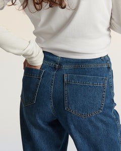 Jean pour femme en denim bleu moyen, coupe droite et fluide, confectionné en coton, offrant un ajustement confortable et adapté à toutes les morphologies.