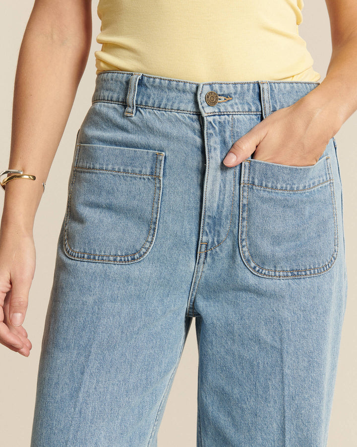 Jean femme en denim bleu clair 100% coton avec coupe droite confortable et poches plaquées devant, idéal pour un style décontracté et moderne.