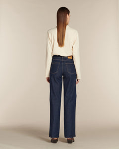 Jean droit long en denim brut 100% coton avec une coupe haute qui met en valeur toutes les morphologies féminines, offrant confort et style intemporel.
porté par le mannequin de dos
