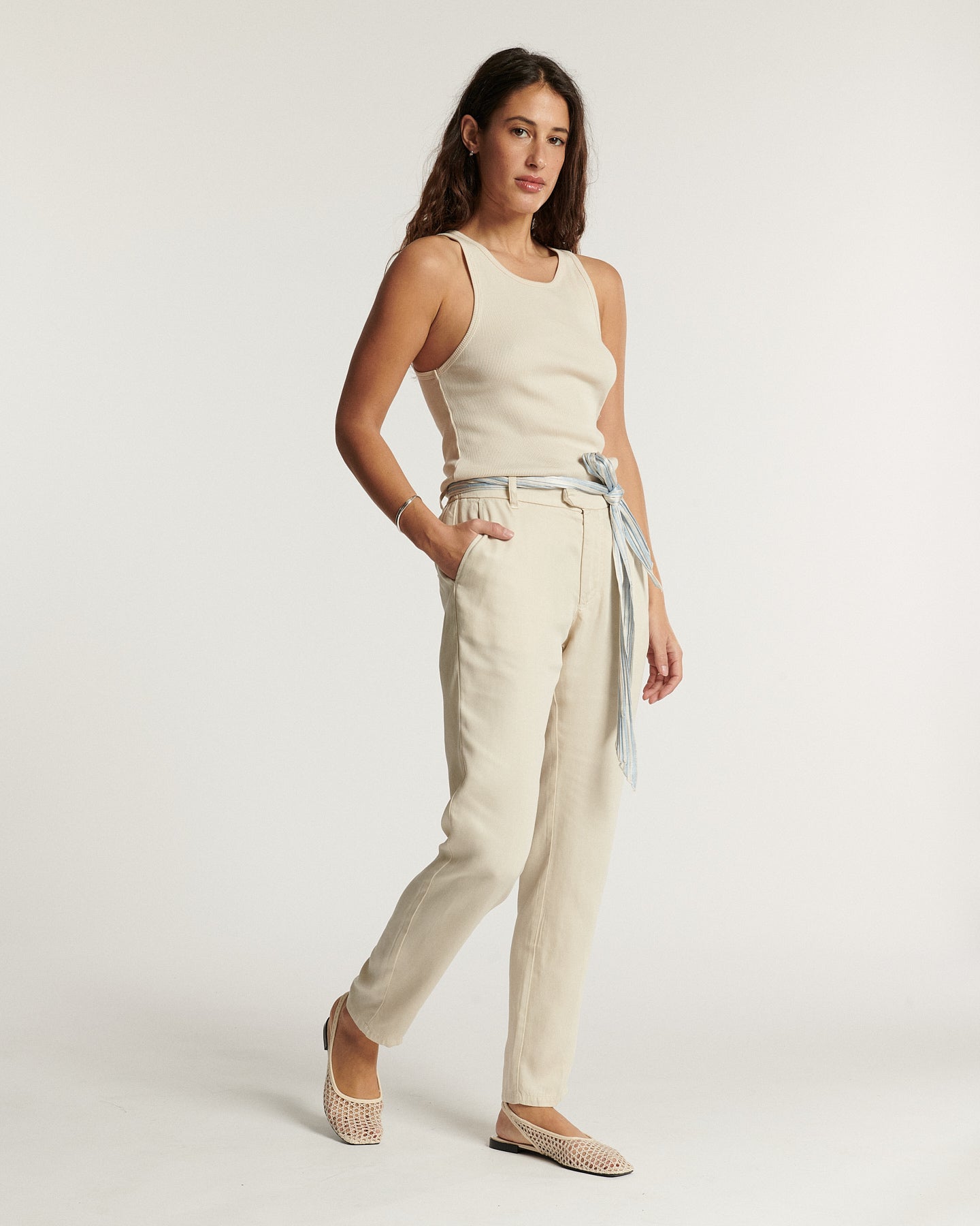 Jean femme en toile légère couleur écume, coupe droite ajustée avec ceinture fine nouée, offrant un confort estival élégant et facile à porter.