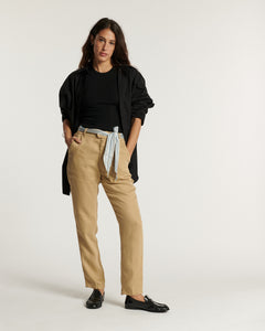 Pantalon beige en tissu Tencel fluide avec coupe droite, taille haute ajustée par une ceinture en tissu rayé bleu clair, adapté à toutes morphologies.