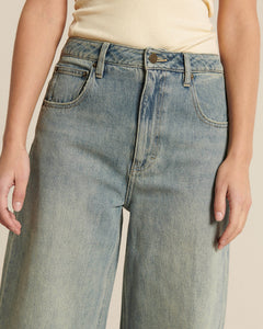 Jean en denim 100 % coton de couleur bleu délavé, coupe large et droite, conçu pour s’adapter à toutes les morphologies féminines avec un effet léger usé.